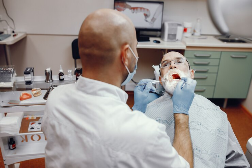 a dentist is checking a senior citizen's teeth