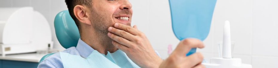 man looking at his teeth after getting dental implant